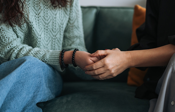 Two people sitting on a couch holding hands, illustrating connection and traits men find attractive in women.