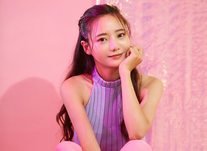 Young woman posing against pink background, highlighting things women do to seem attractive men can't stand.