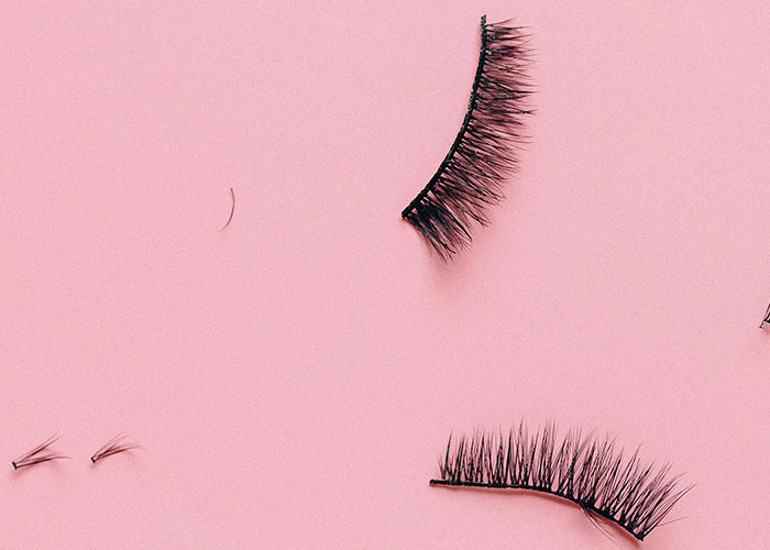 False eyelashes arranged on a pink background symbolizing dramatic and wild experiences shared about ex relationships.