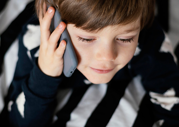 Young boy holding a phone to his ear, illustrating 911 operators handling dumbest non-emergency calls they've received.