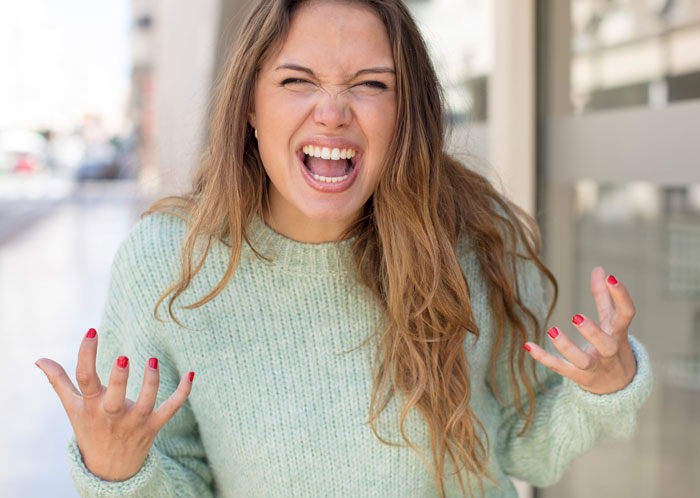 Angry young woman expressing intense frustration outdoors, illustrating repressed rage at mother-in-law conflict.