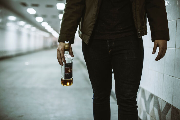 Person holding a bottle of rum in a dimly lit corridor symbolizing unintended big family drama moments.