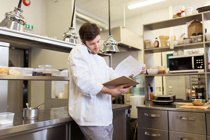 Chef employee in commercial kitchen reviewing documents, revealing dark and dirty truths about their industry.