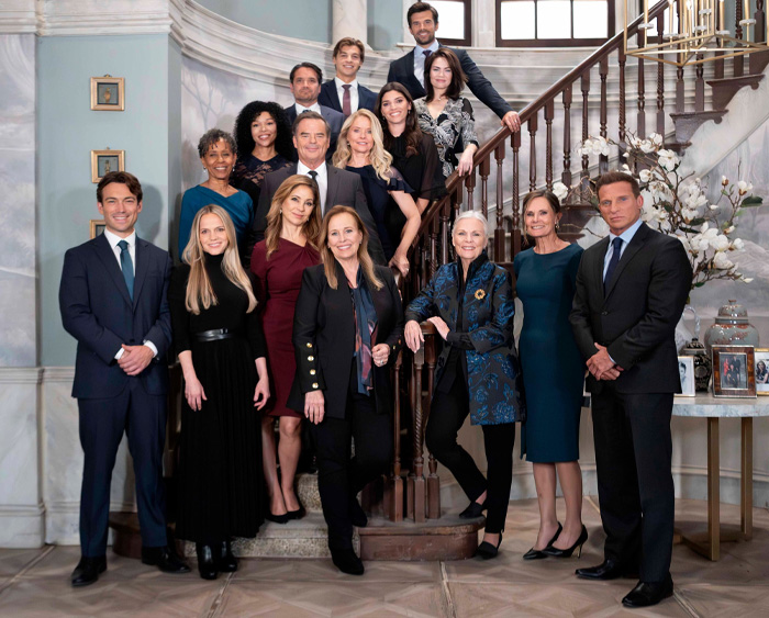 Cast members posing on a grand staircase representing one of the longest running TV shows of all time in formal attire.