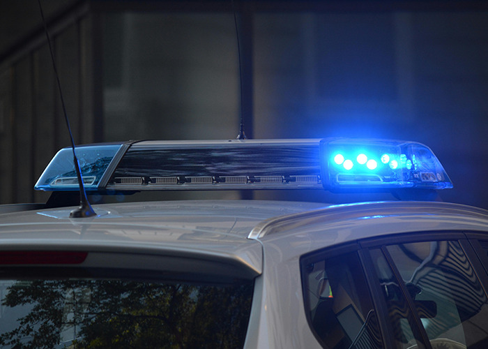 Close-up of a police car roof with blue flashing lights, related to 911 operators and non-emergency calls.