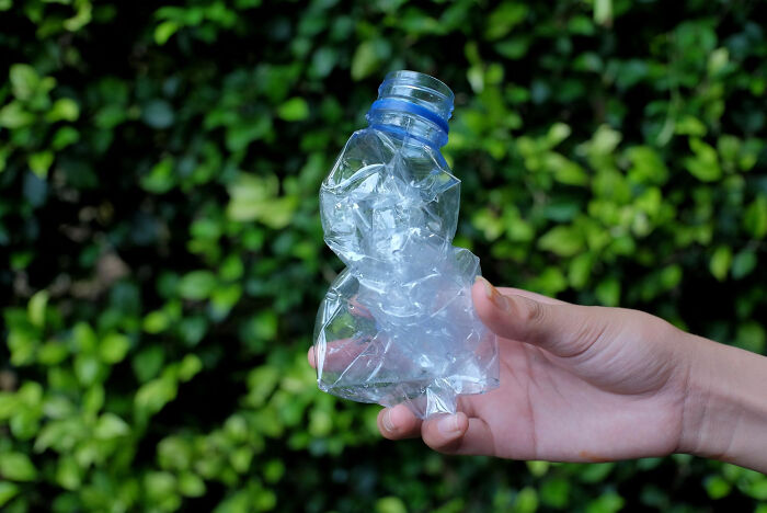 Person holding a crushed plastic bottle representing dark dirty truths revealed by employees about their industries.