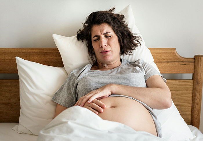 Pregnant woman in pain lying in bed, depicting challenges faced by a childfree woman refusing responsibility for new baby. Pregnant woman in pain lying in bed, depicting challenges faced by a childfree woman refusing responsibility for new baby.