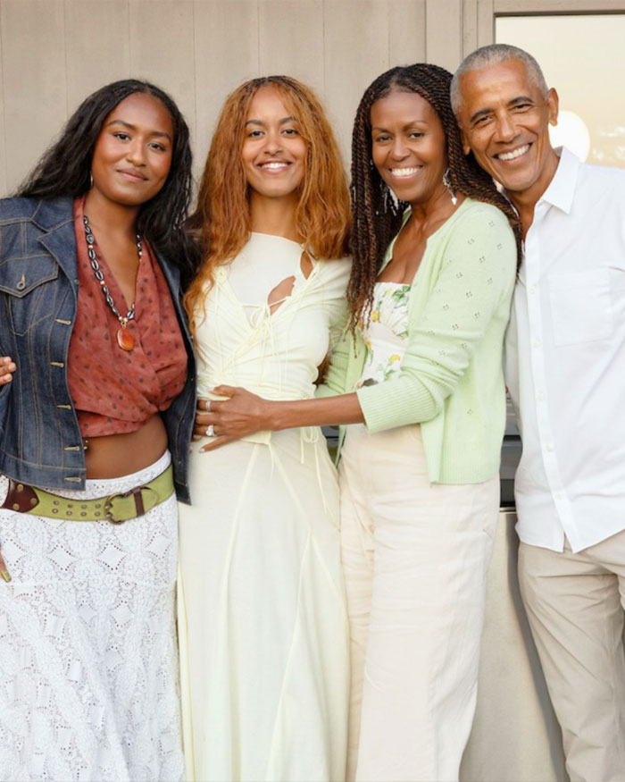 Michelle Obama and family smiling together, showcasing her bold new look praised by makeup artist. Michelle Obama and family smiling together, showcasing her bold new look praised by makeup artist.