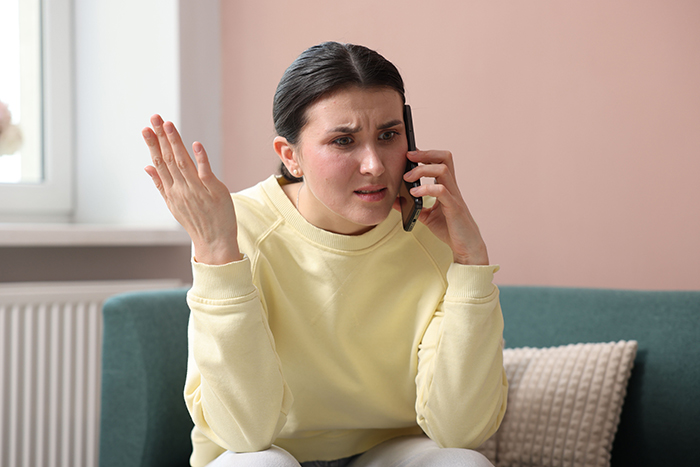 Woman in yellow sweater on phone looking frustrated, illustrating family allergy conflict and reality check situation. Woman in yellow sweater on phone looking frustrated, illustrating family allergy conflict and reality check situation.