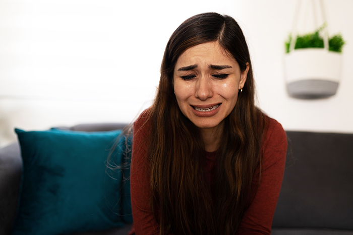 Young woman in a red top crying on a couch, illustrating emotional pain from marriage falling apart after wedding troubles. Young woman in a red top crying on a couch, illustrating emotional pain from marriage falling apart after wedding troubles.
