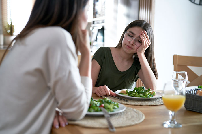 Woman loses appetite after seeing how mother-in-law prepares chicken, sitting at a dining table with salad plates and juice. Woman loses appetite after seeing how mother-in-law prepares chicken, sitting at a dining table with salad plates and juice.