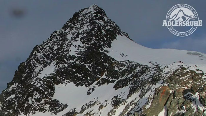 Snow-covered peak of Austria’s highest mountain with hikers in distance, related to woman abandoned and fatally frozen case. Snow-covered peak of Austria’s highest mountain with hikers in distance, related to woman abandoned and fatally frozen case.