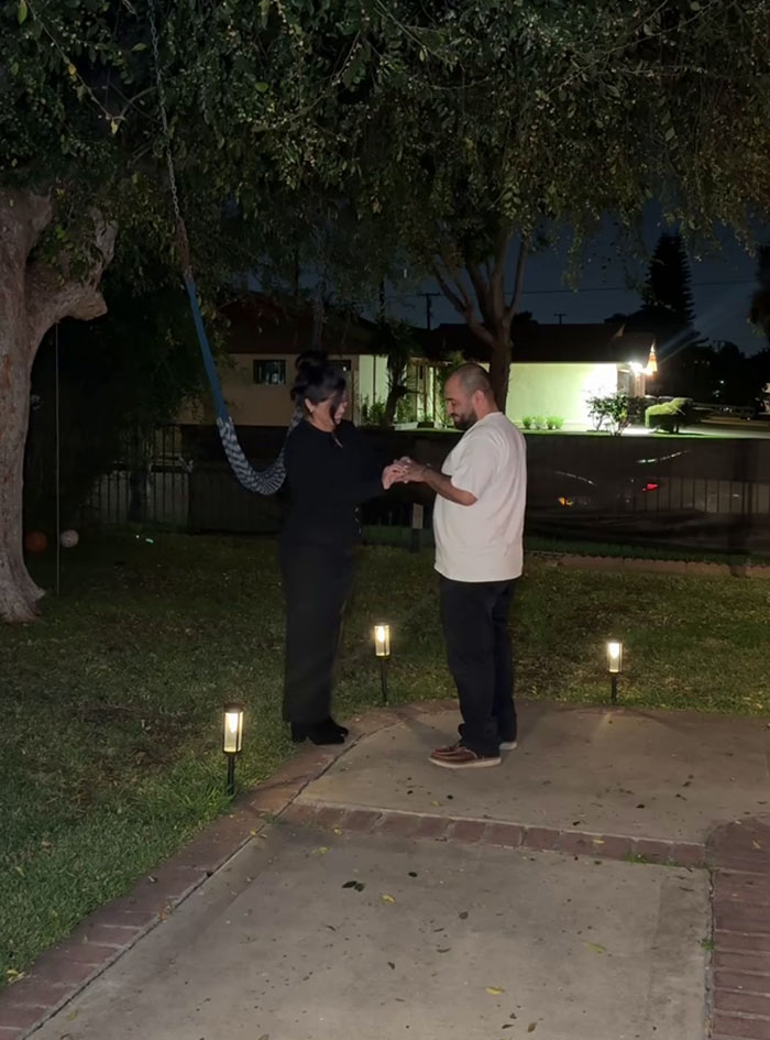 Woman proposing to her boyfriend of 14 years in a backyard at night with small lights along the path. Woman proposing to her boyfriend of 14 years in a backyard at night with small lights along the path.