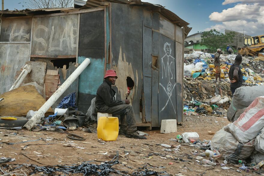 Man sitting outside a rundown structure surrounded by trash and debris in one of the dirtiest countries by pollution rankings Man sitting outside a rundown structure surrounded by trash and debris in one of the dirtiest countries by pollution rankings