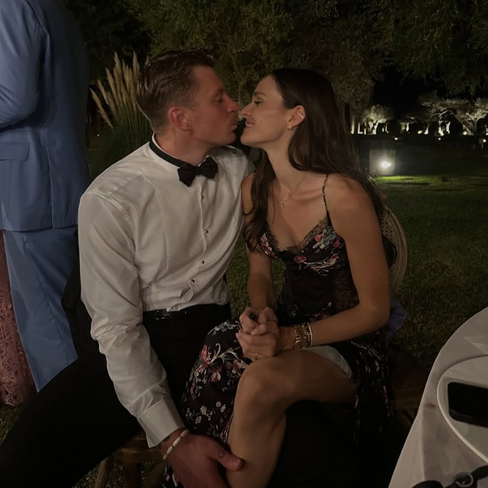 Couple sharing a tender moment at an outdoor evening event, with focus on a satin bed sheet inspired dress.