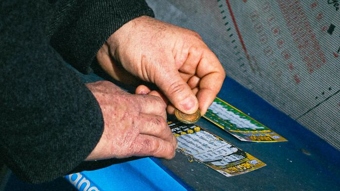 Person scratching a lottery ticket with a coin, symbolizing casting vote in ambiguous situations debate.