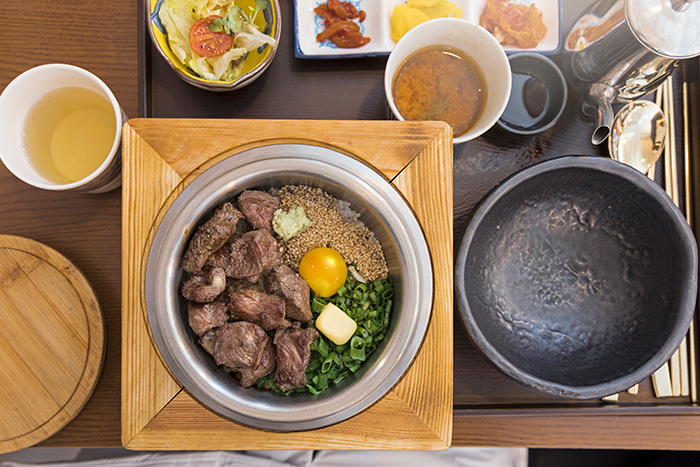 At-home date night ideas featuring a homemade meal with steak, egg yolk, and fresh vegetables served on a wooden tray.