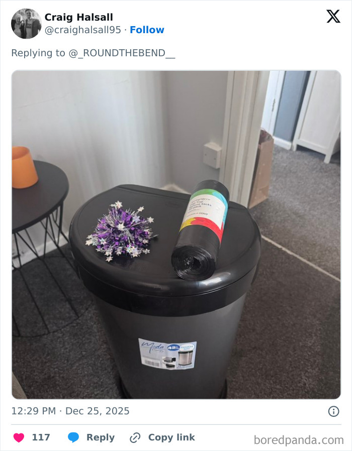 Black trash bin with purple tinsel and a roll of bin bags on top, an example of worst Xmas presents received.