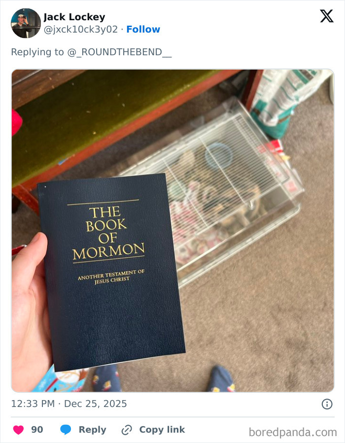 Hand holding The Book of Mormon next to a small animal cage on carpet showing one of the worst Xmas presents people received.