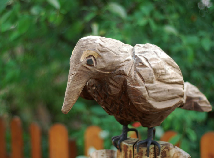 Carved wooden bird sculpture perched outdoors in the woods, symbolizing people who couldn't sleep after time in nature.