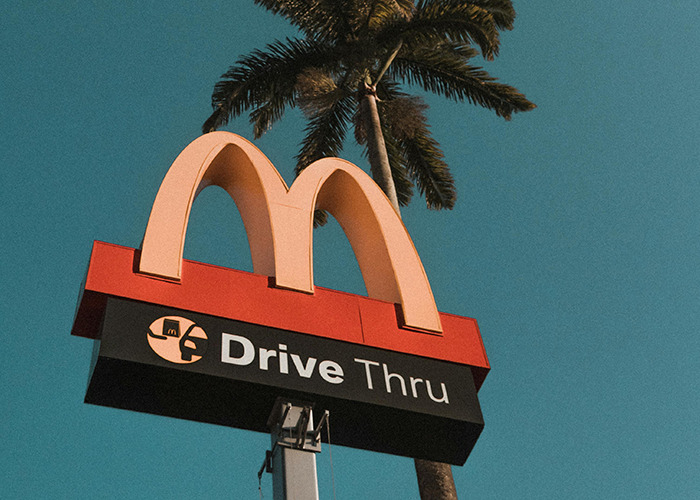 McDonald's drive thru sign under clear sky with palm tree, illustrating unexpected 911 operators non-emergency calls.