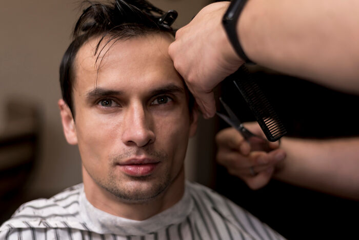Man getting a haircut while reflecting on crazy things people have done to make their ex pine for them.