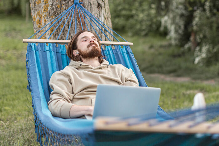 Man relaxing in a hammock outdoors using a laptop, illustrating small tricks that make being a grown-up easier.