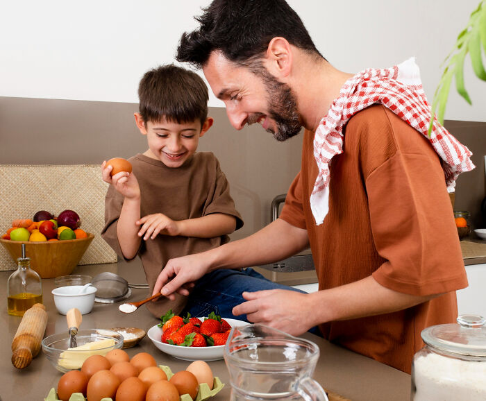 Man and child cooking together preparing ingredients in kitchen, men missed delivery babies concept.