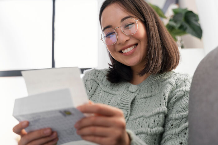 Young woman smiling while reading a letter, illustrating emotional moments of people who believe their ex will always pine for them.