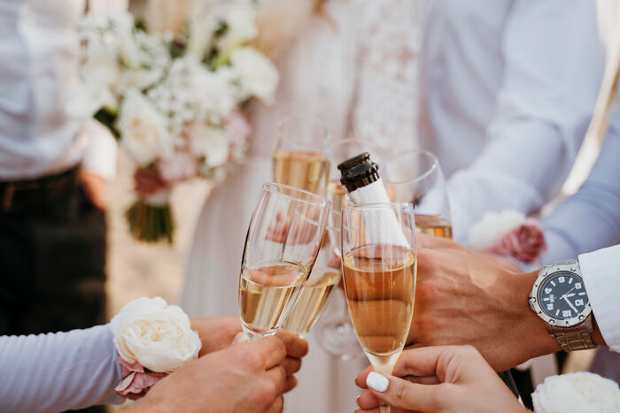 People toasting with champagne glasses at a wedding, capturing moments of unexpected big family drama.