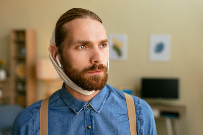 Man with a serious expression wearing earphones and a face mask under his chin, reflecting on revenge stories with bitter aftertaste.