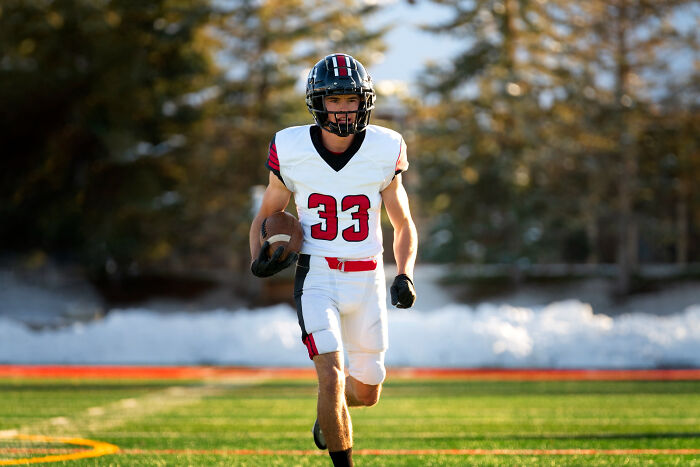 Young football player in a black and white uniform running on field, illustrating once famous regular job activity.