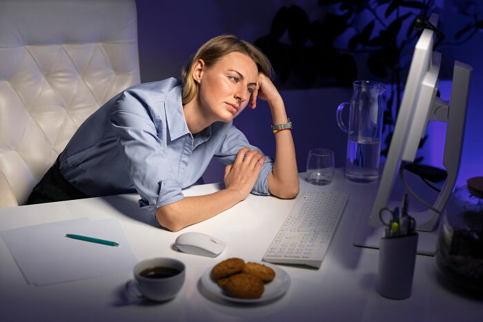 Woman at desk looking frustrated in front of computer, illustrating infuriating work experiences with old habits.