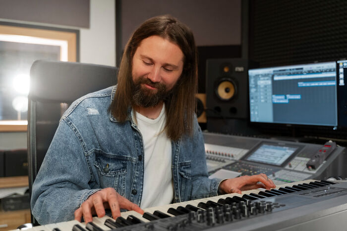 Once-famous musician with a regular job playing keyboard in a recording studio with audio equipment and computer screen.