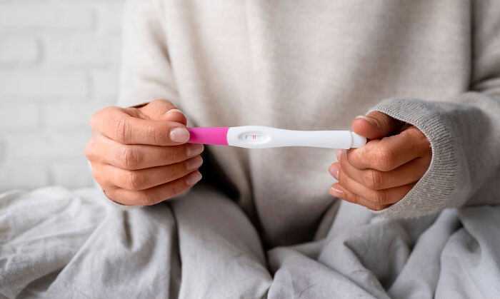Person holding a positive pregnancy test, illustrating disturbing science facts about human biology and reproduction.