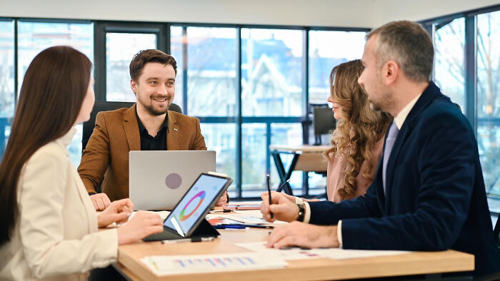 Four coworkers sharing an awkward moment during a meeting, an embarrassing moment people were blessed to see.