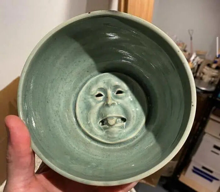 Ceramic bowl with a trippy face sculpted inside, creating surreal and otherworldly vibes.