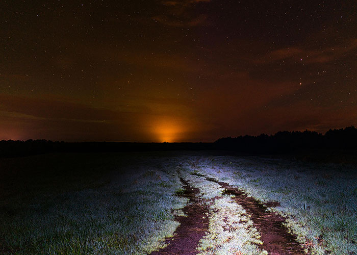 Dark rural path illuminated under a starry sky, evoking creepy and mysterious scenes in remote and isolated places.