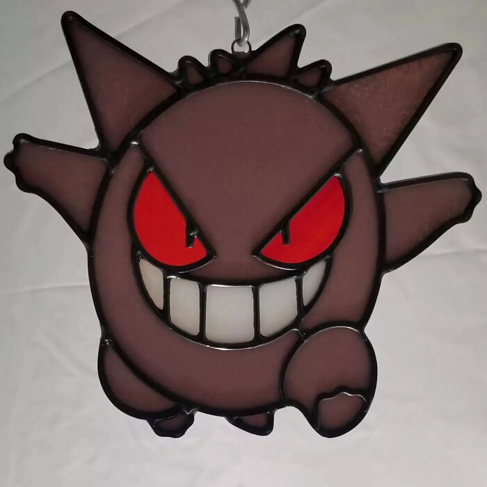 Stained glass sign featuring a vivid pop culture icon with red eyes and a mischievous grin.