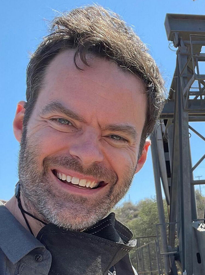 Close-up of Bill Hader smiling outdoors with a blue sky background, linked to a tense moment with Rob Reiner&rsquo;s son Nick.