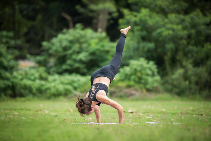 Woman practicing advanced yoga pose outdoors, showcasing flexibility during embarrassing moments many were blessed to witness.