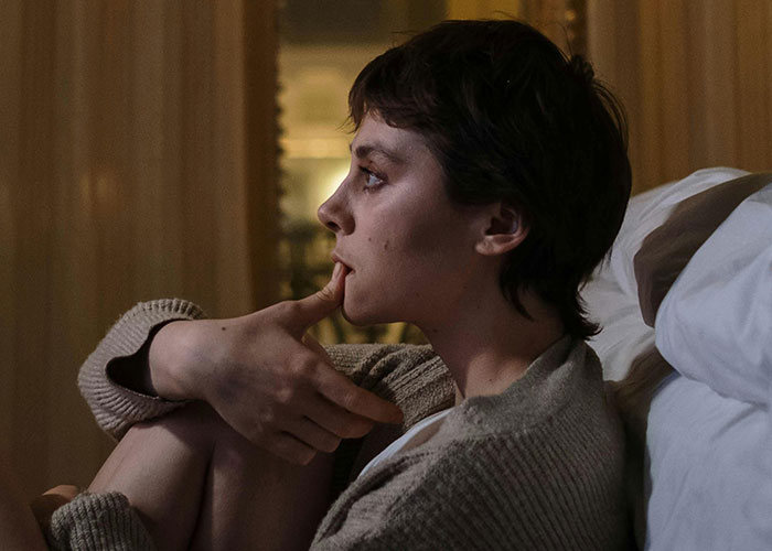 Person sitting on bed looking pensive, illustrating emotions tied to the most insane thing an ex ever did stories.