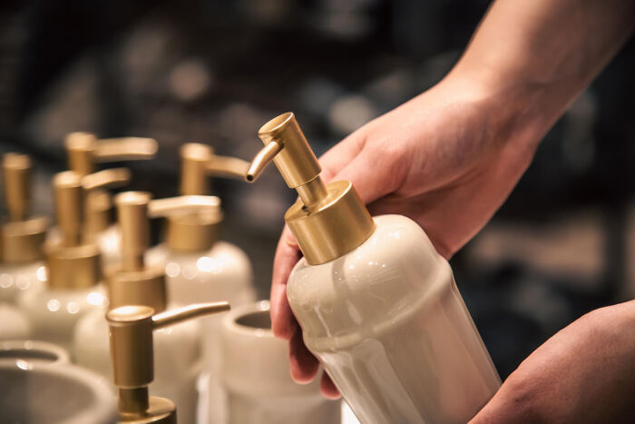 Person holding a white and gold soap dispenser among similar bathroom design items revealing small design mistakes.