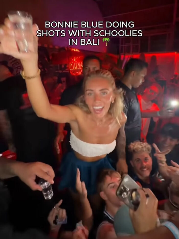 Bonnie Blue raising a shot glass in a crowded Bali club, surrounded by people enjoying a night out and taking photos. Bonnie Blue raising a shot glass in a crowded Bali club, surrounded by people enjoying a night out and taking photos.