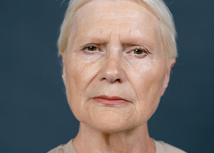 Close-up of a serious older woman with short white hair, illustrating shock and unhinged things her MIL just said to them.