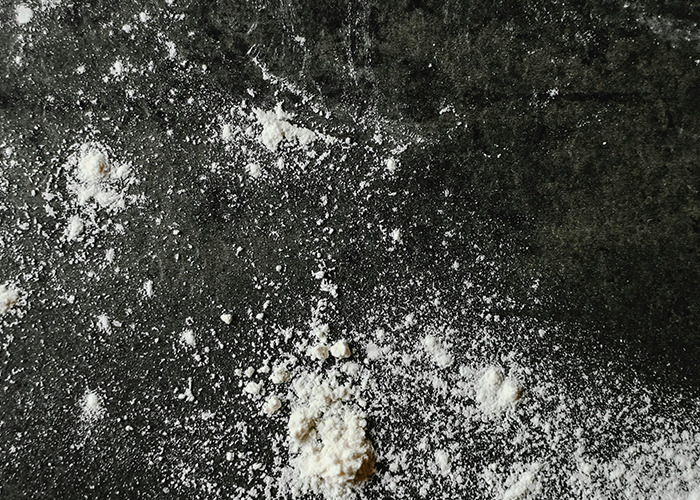 White powder spilled on a dark textured surface representing a scene related to 911 operators and non-emergency calls.