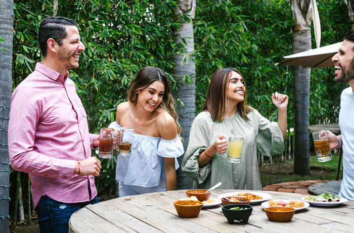 Four friends enjoying drinks and food outdoors, with the brother making his bill pay dinner in a relaxed setting. Four friends enjoying drinks and food outdoors, with the brother making his bill pay dinner in a relaxed setting.