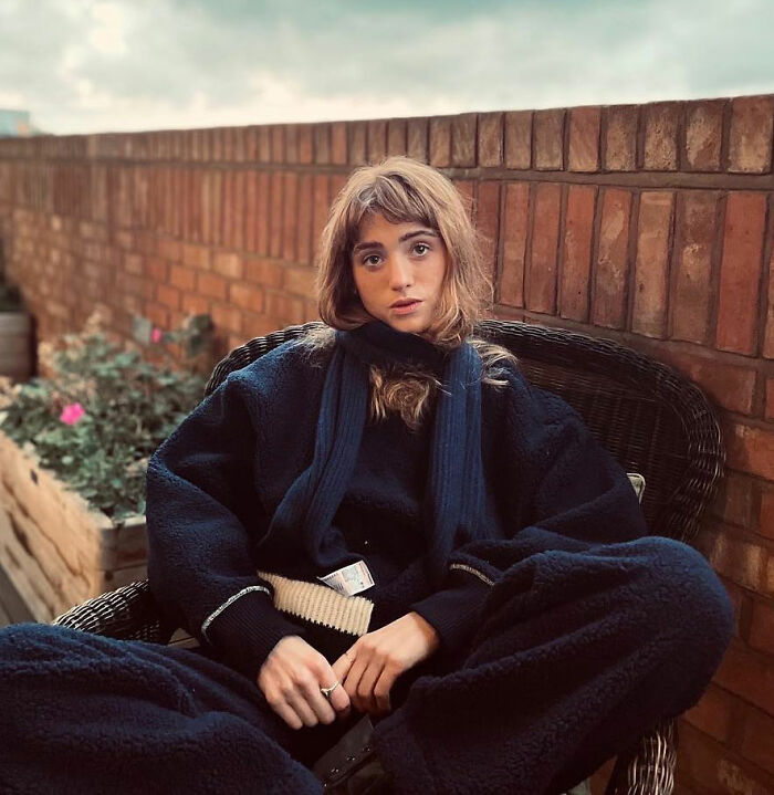 Stranger Things star Natalia Dyer sitting outdoors in dark cozy clothes, with a thoughtful expression and soft natural light. Stranger Things star Natalia Dyer sitting outdoors in dark cozy clothes, with a thoughtful expression and soft natural light.