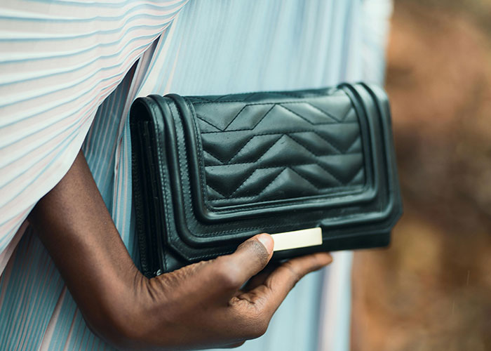 Person holding a black luxury leather clutch bag, illustrating items people who work in luxury industries discuss.