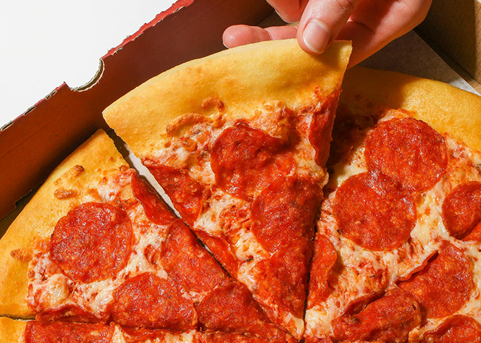 Close-up of a hand lifting a slice of pepperoni pizza from a box, related to 911 operators and non-emergency calls.